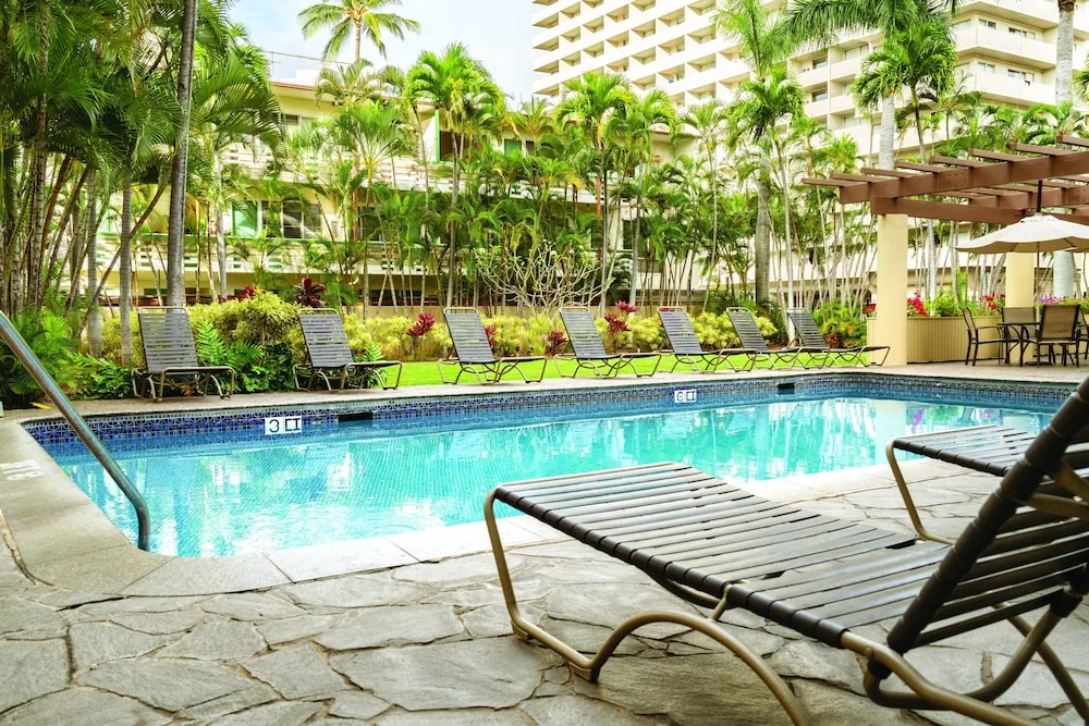 Outdoor pool with lounge chairs and palm landscaping at Club Wyndham Royal Garden at Waikiki.