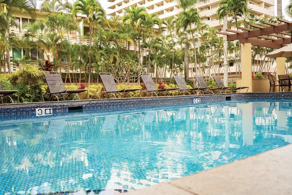 Outdoor pool with lounge chairs and palms at Club Wyndham Royal Garden at Waikiki.
