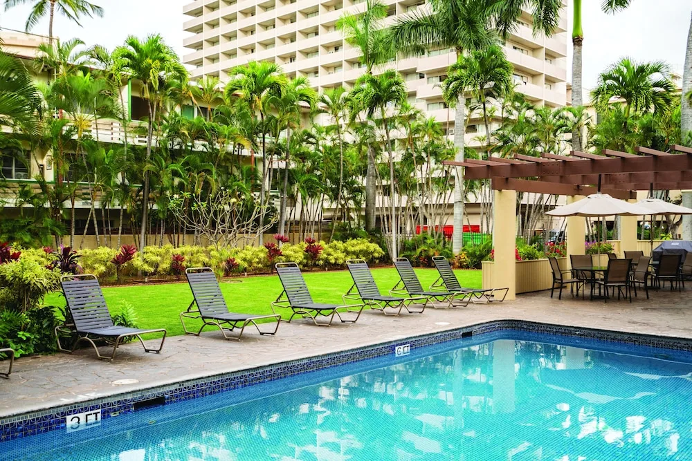 Pool deck with loungers, lawn, and pergola at Club Wyndham Royal Garden at Waikiki.