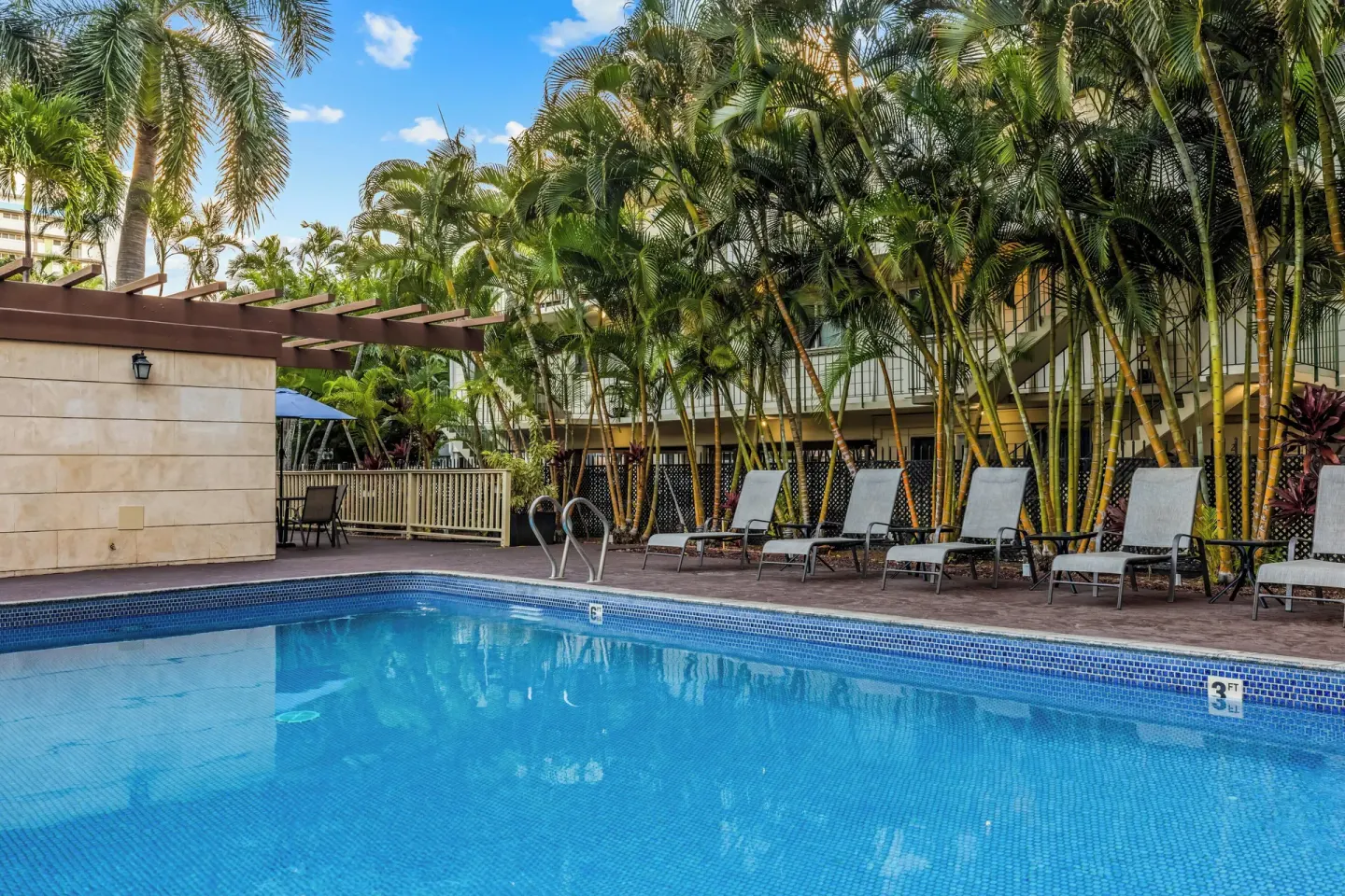 Pool with lounge chairs and palms at Club Wyndham Royal Garden at Waikiki.