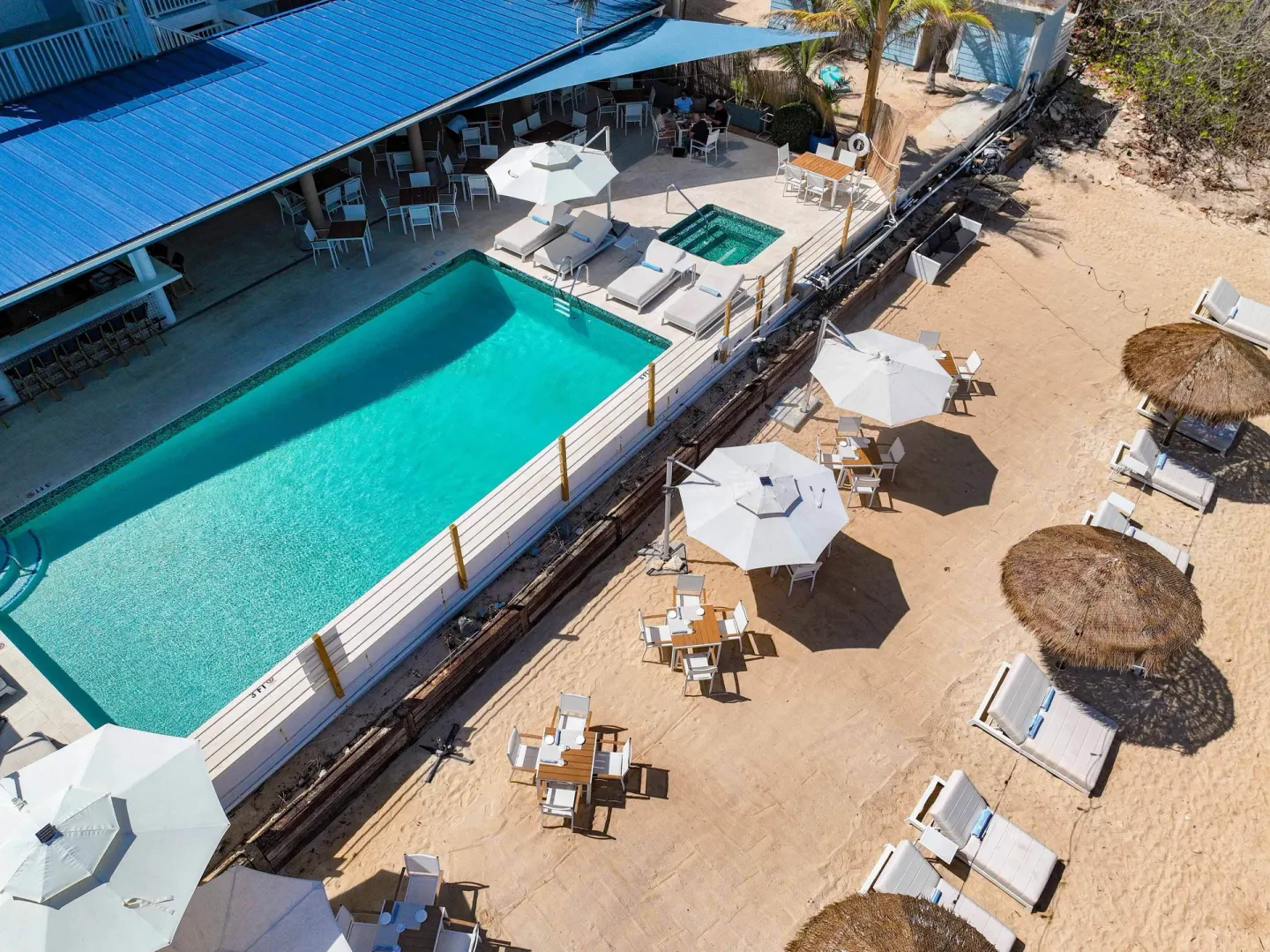 Aerial view of the pool deck, beach seating, umbrellas, and loungers at Cobalt Coast Resort.