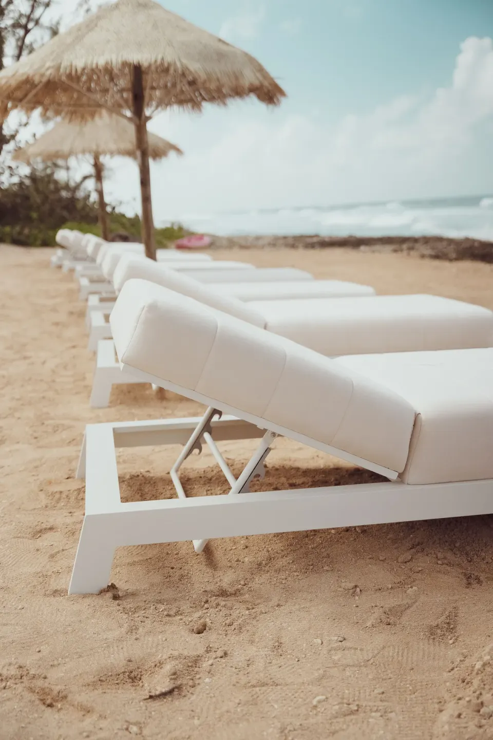 White beach loungers under thatched umbrellas at Cobalt Coast Resort.