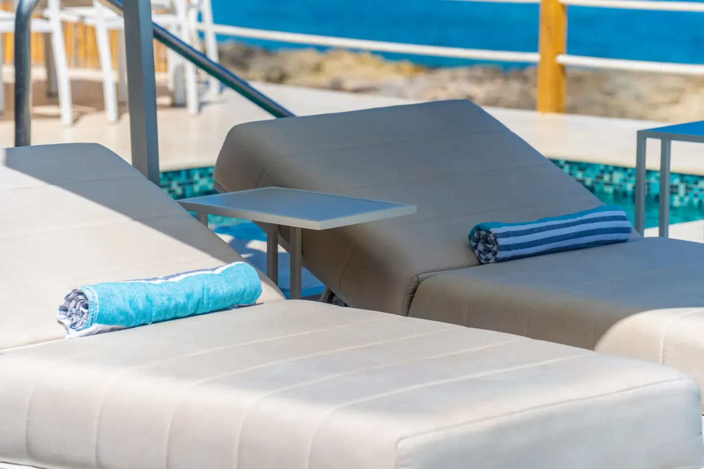 Close-up of cushioned pool loungers with rolled towels at Cobalt Coast Resort.