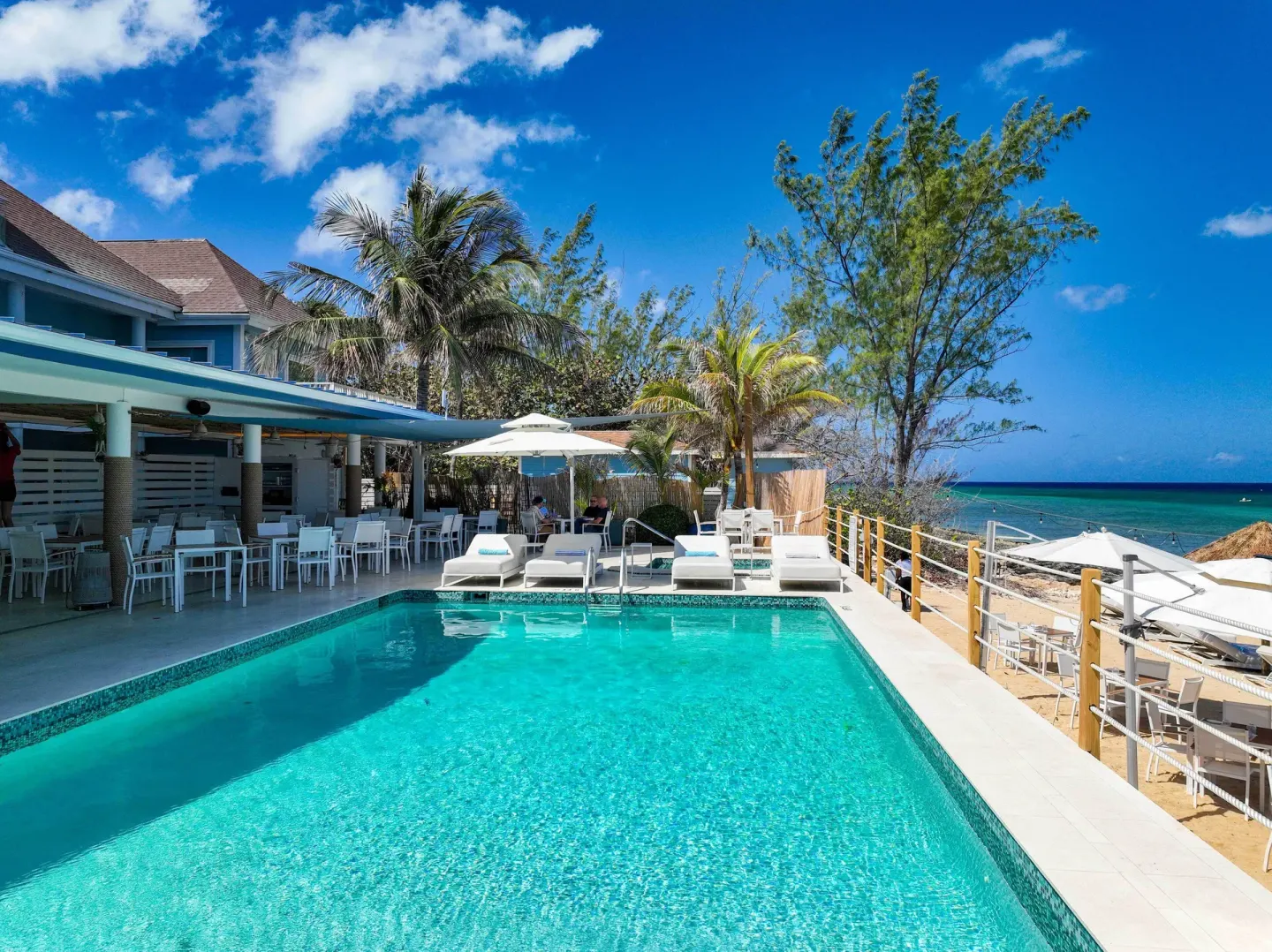 Oceanfront pool with loungers, umbrellas, and dining tables at Cobalt Coast Resort.