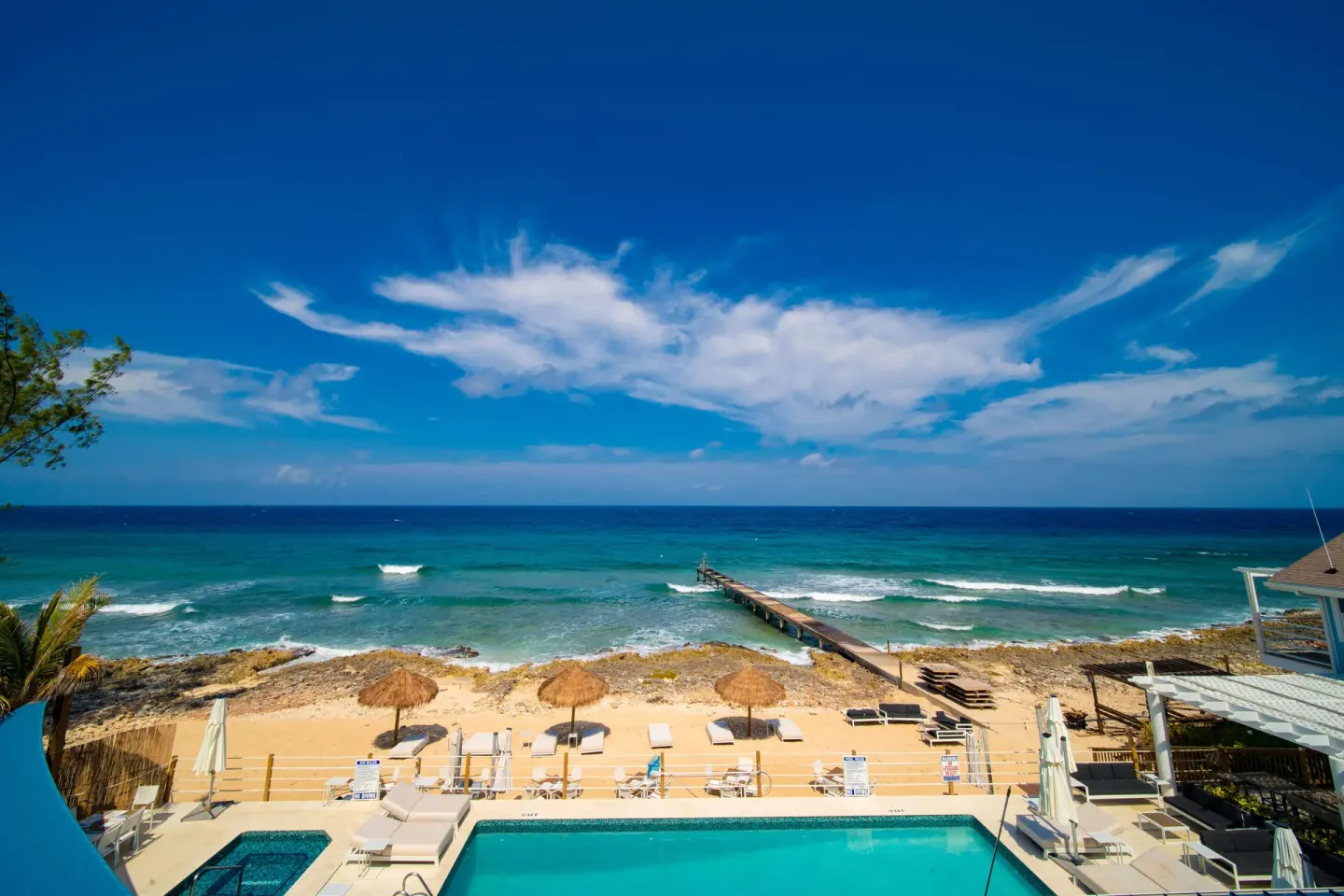 Pool, beach, pier, and blue ocean at Cobalt Coast Resort.