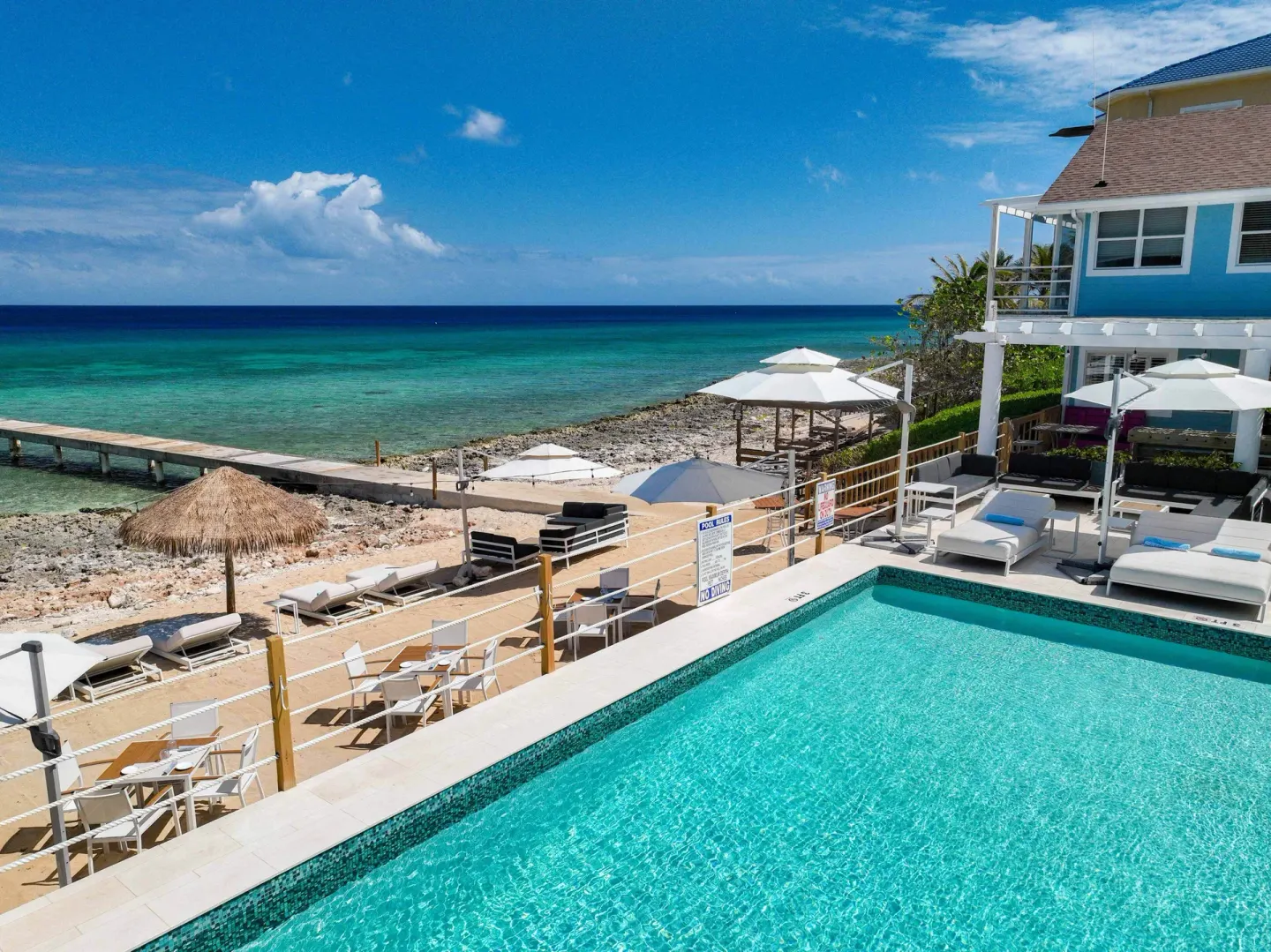 Pool edge, beach loungers, pier, and ocean at Cobalt Coast Resort.