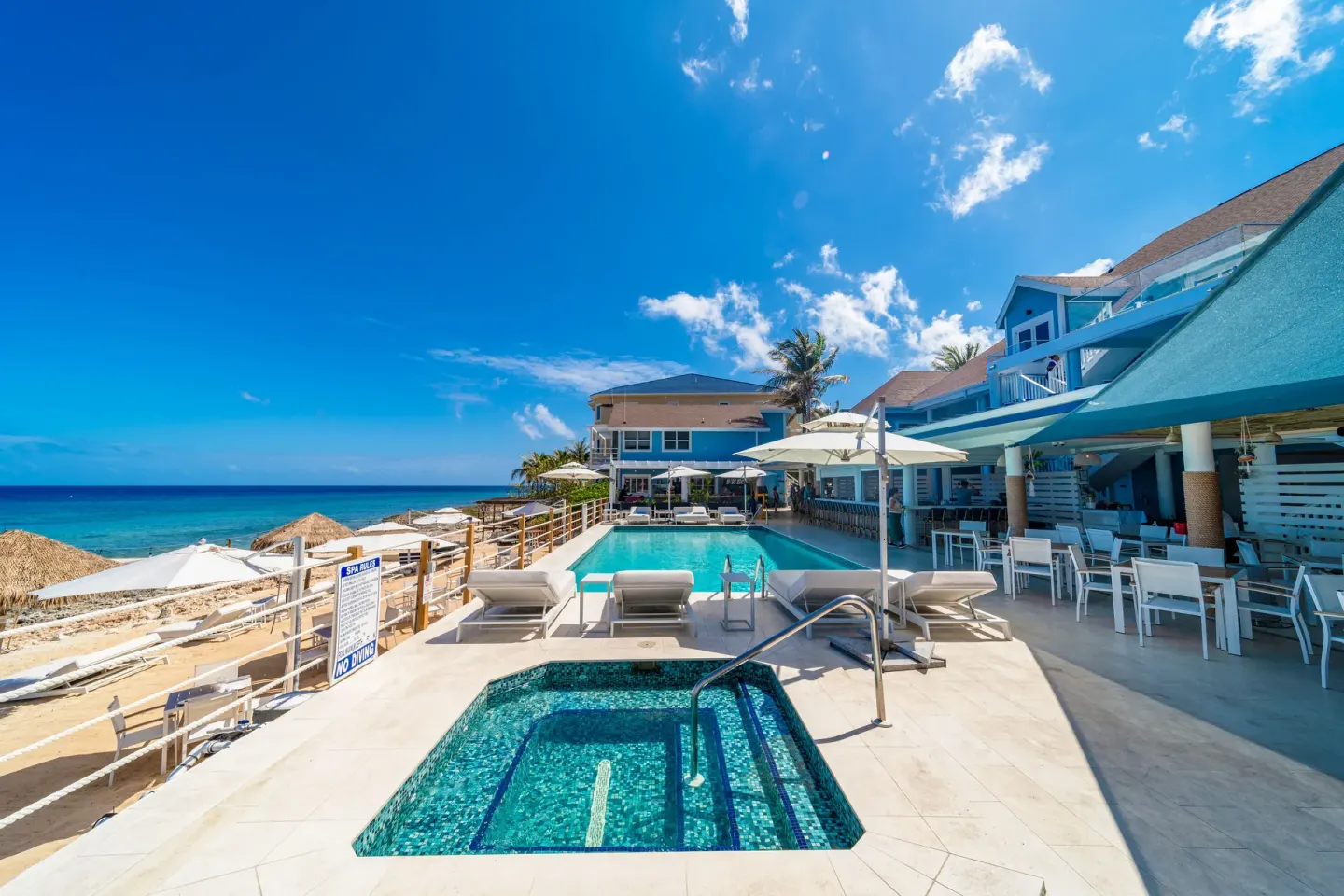 Pool, spa pool, umbrellas, and oceanfront buildings at Cobalt Coast Resort.