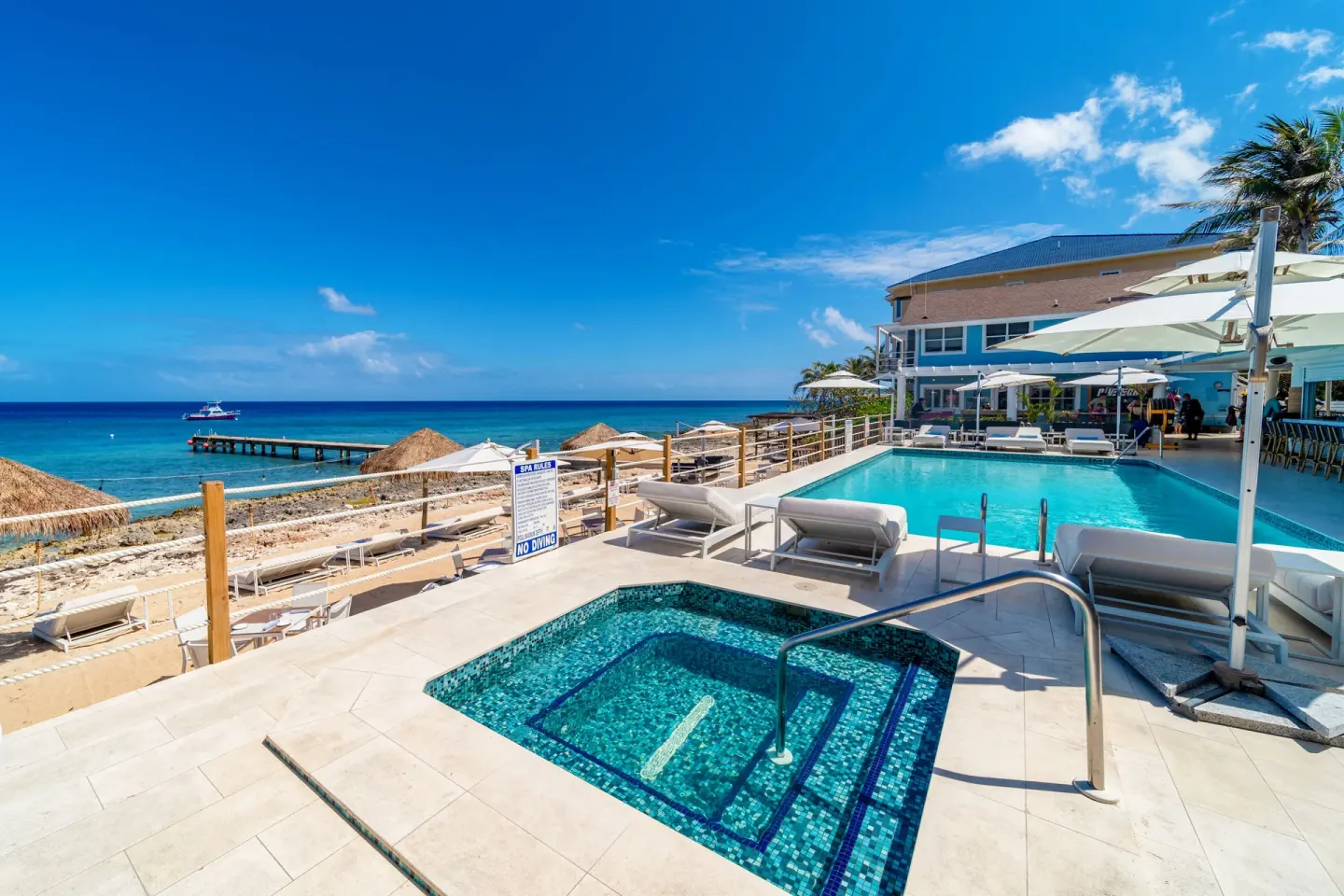 Spa pool, main pool, loungers, pier, and ocean at Cobalt Coast Resort.