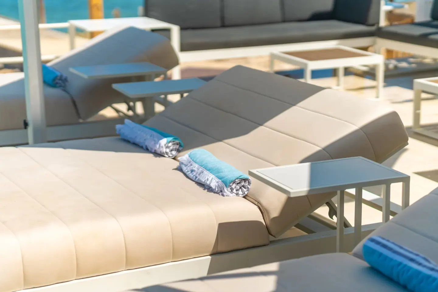 Sunlit cushioned loungers with rolled towels and side tables at Cobalt Coast Resort.