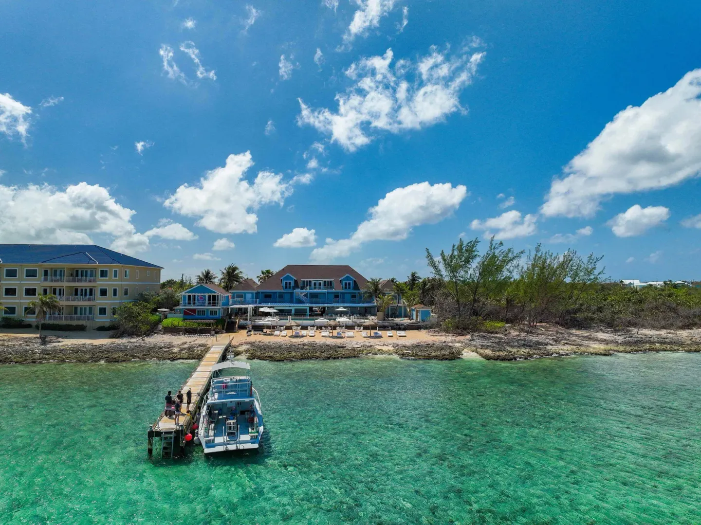 Pier, dive boat, beach, and waterfront buildings at Cobalt Coast Resort.