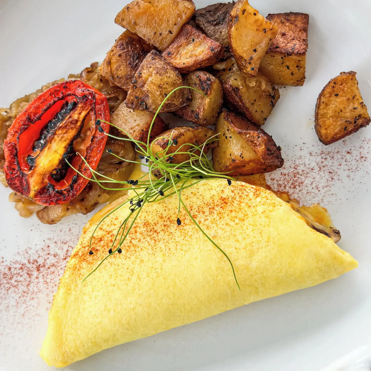 Omelet with roasted potatoes, grilled tomato, and greens at Cobalt Coast Resort.