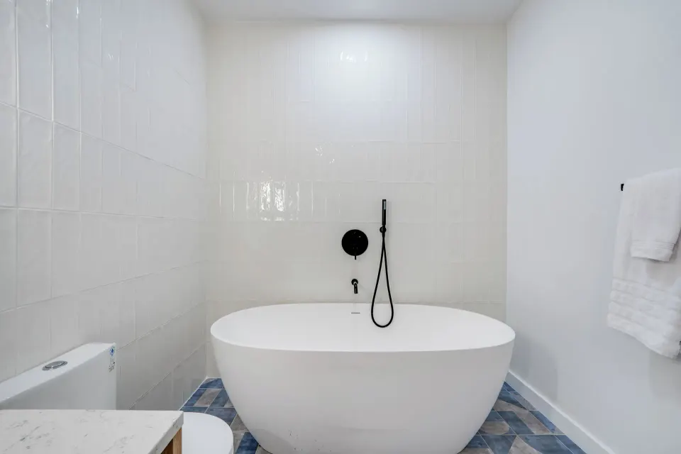 Deluxe Room bathroom freestanding tub with black hand shower at Cobalt Coast Resort.