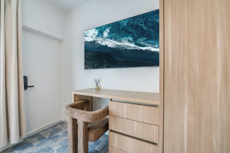 Deluxe Room desk, chair, dresser, and wall-mounted TV at Cobalt Coast Resort.