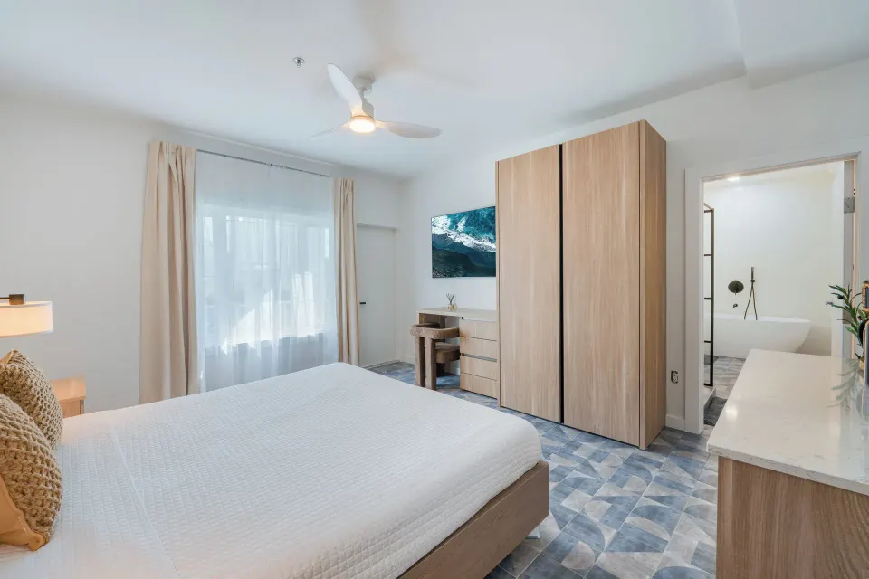 Deluxe Room king bed, wardrobe, desk, and open bathroom doorway at Cobalt Coast Resort.