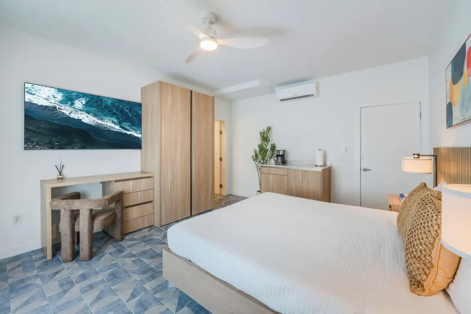 Deluxe Room king bed, desk, wardrobe, coffee cabinet, and TV at Cobalt Coast Resort.