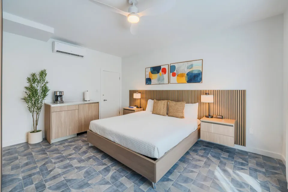 Deluxe Room king bed with slatted headboard and bedside lamps at Cobalt Coast Resort.