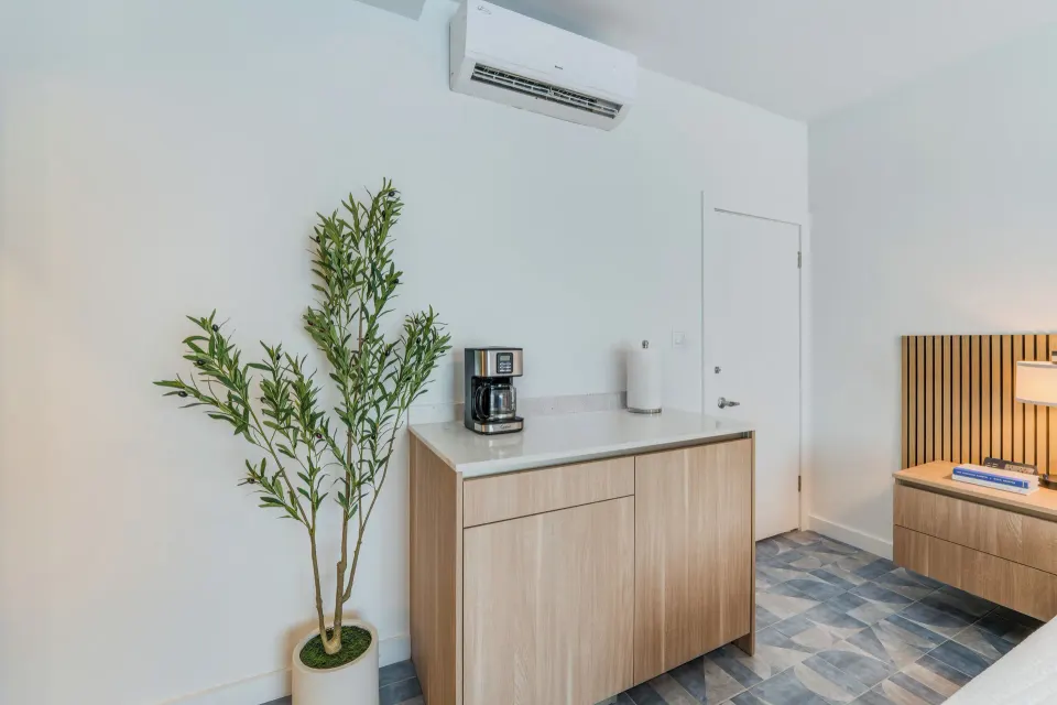 Deluxe Room refreshment cabinet with coffee maker and plant at Cobalt Coast Resort.