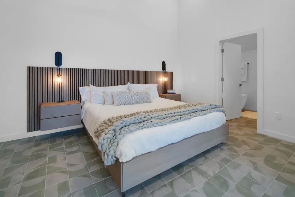 Corner Ocean View bed with slatted headboard and open bathroom doorway at Cobalt Coast Resort.