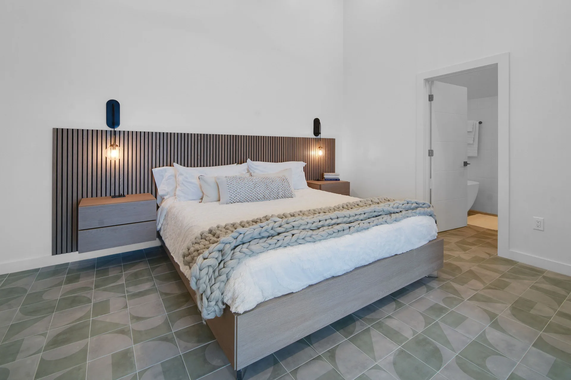 Corner Ocean View bed with slatted headboard and open bathroom doorway at Cobalt Coast Resort.