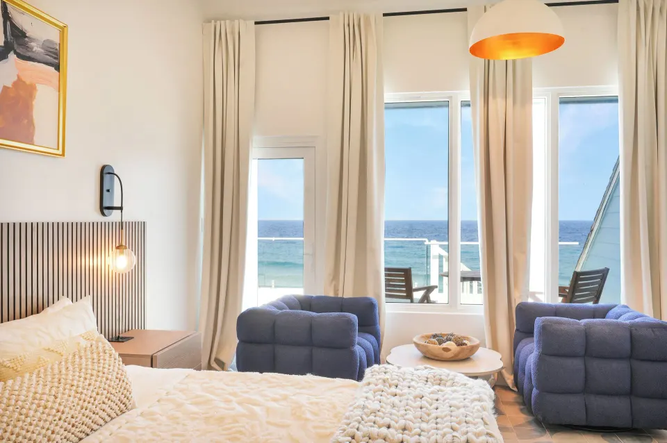 Ocean View room sitting area with blue chairs and sea-facing windows at Cobalt Coast Resort.