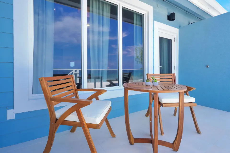 Ocean View room patio with wood chairs and table at Cobalt Coast Resort.
