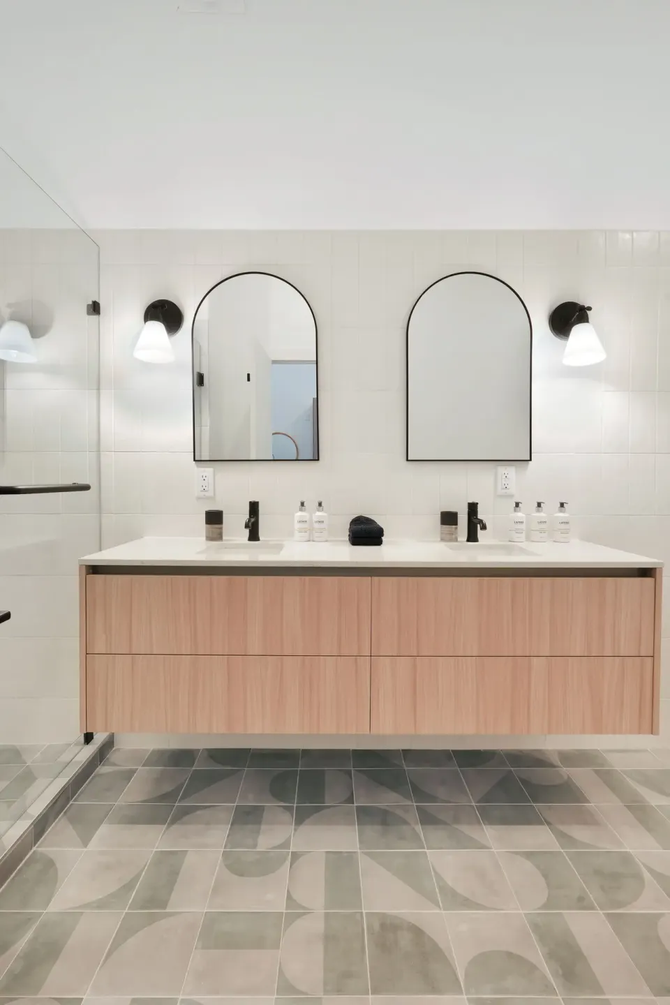 Signature Room bathroom double vanity with arched mirrors and glass shower at Cobalt Coast Resort.