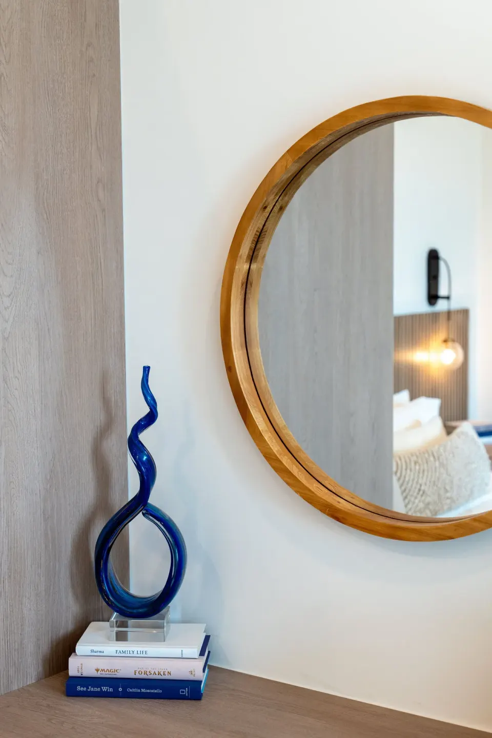 Signature Room dresser detail with round mirror, blue sculpture, and books at Cobalt Coast Resort.