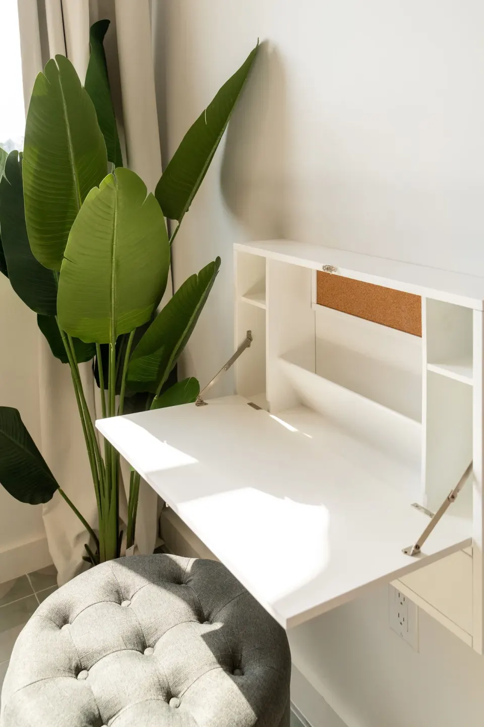Signature Room fold-down desk with cushioned stool and leafy plant at Cobalt Coast Resort.