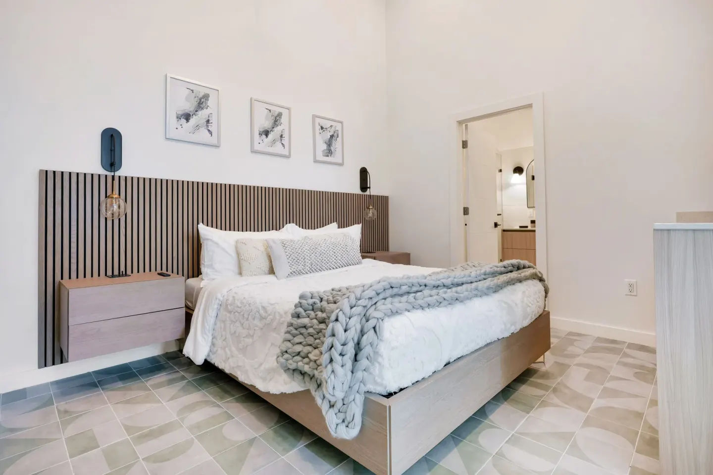 Signature Room king bed with wood slat headboard and open bathroom doorway at Cobalt Coast Resort.