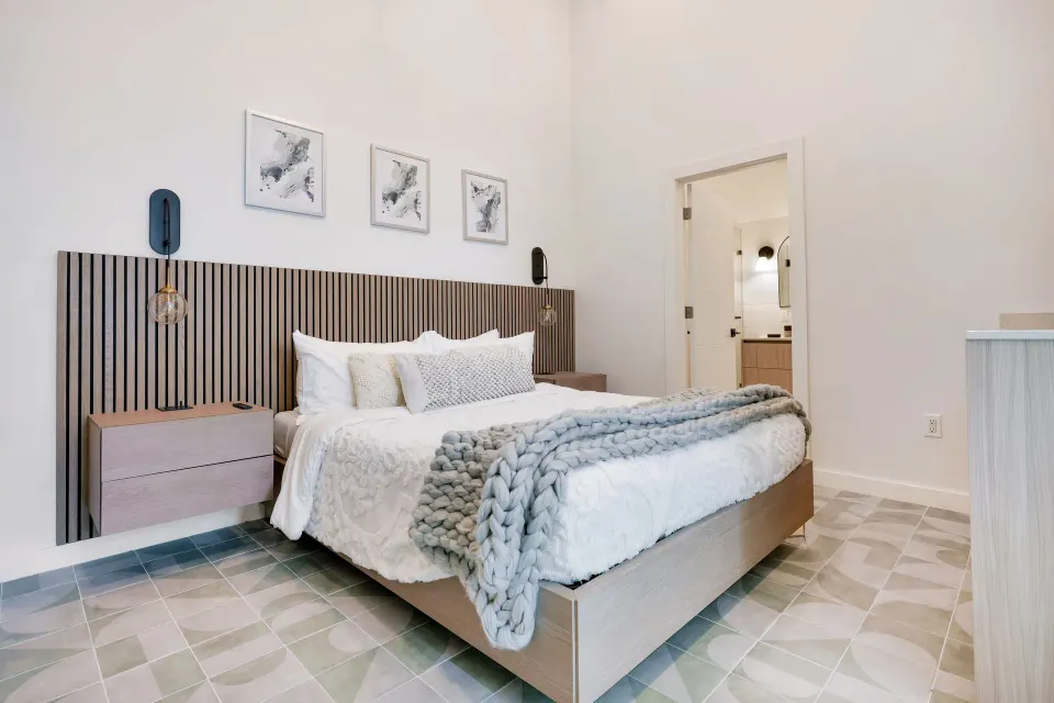 Signature Room king bed with wood slat headboard and open bathroom doorway at Cobalt Coast Resort.