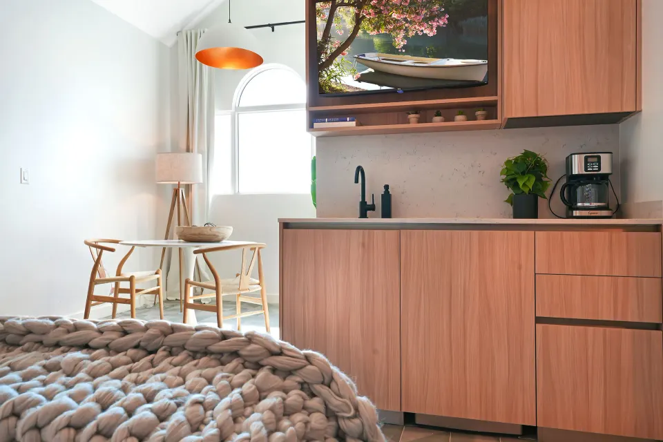 Signature Room kitchenette with sink, coffee maker, TV, and dining table at Cobalt Coast Resort.