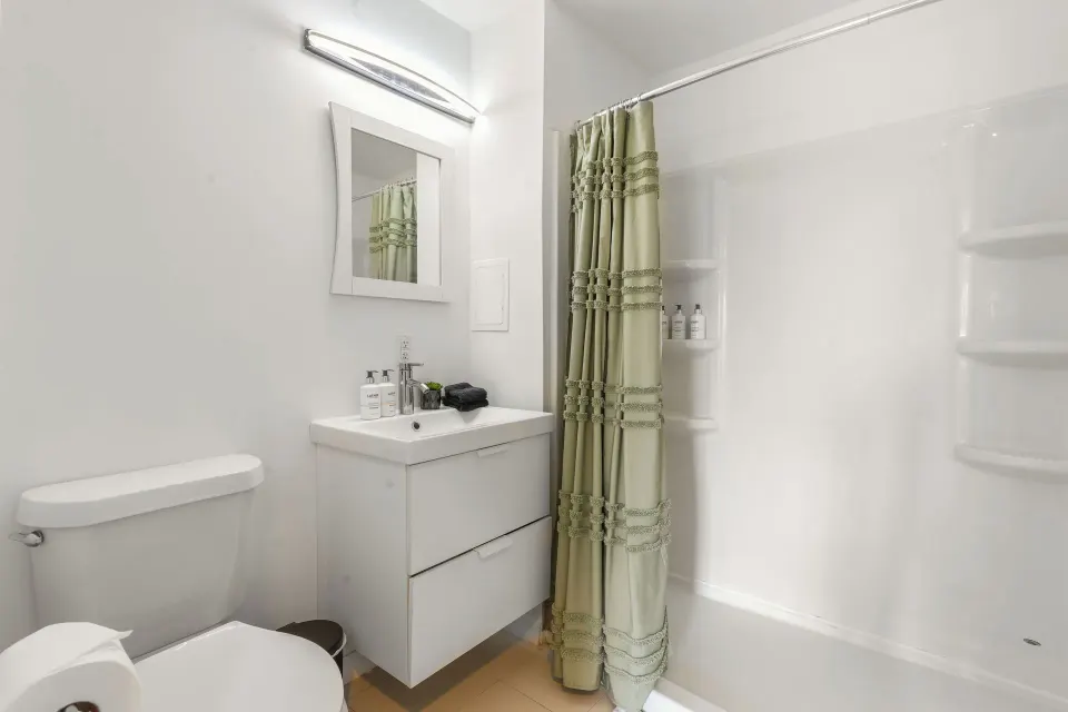 Standard Room bathroom with vanity, toilet, and curtained tub shower at Cobalt Coast Resort.