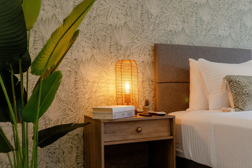 Standard Room bedside table with lamp, plant and partial bed at Cobalt Coast Resort.