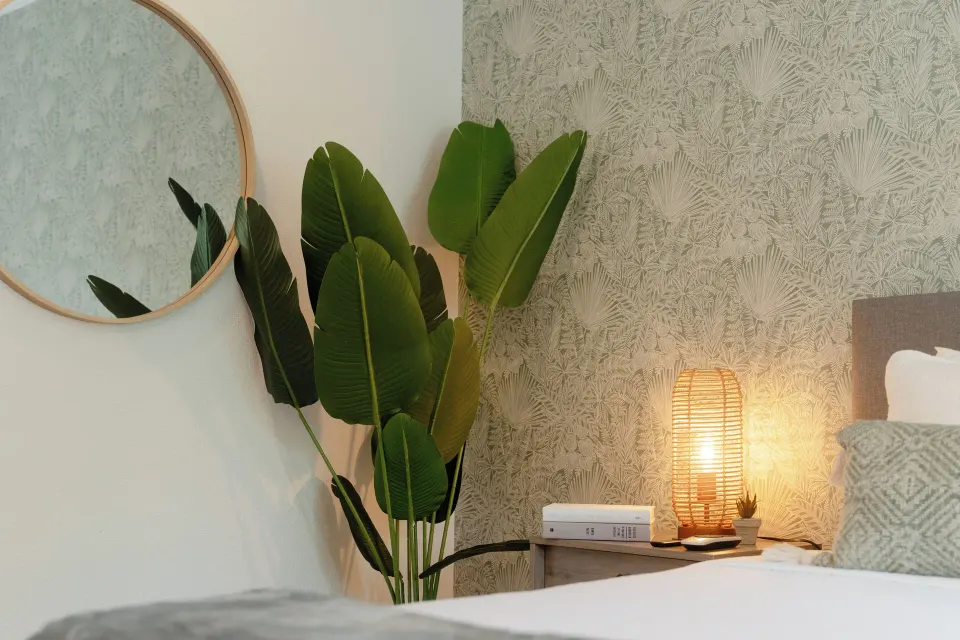 Standard Room corner with plant, mirror, bedside lamp and bed at Cobalt Coast Resort.