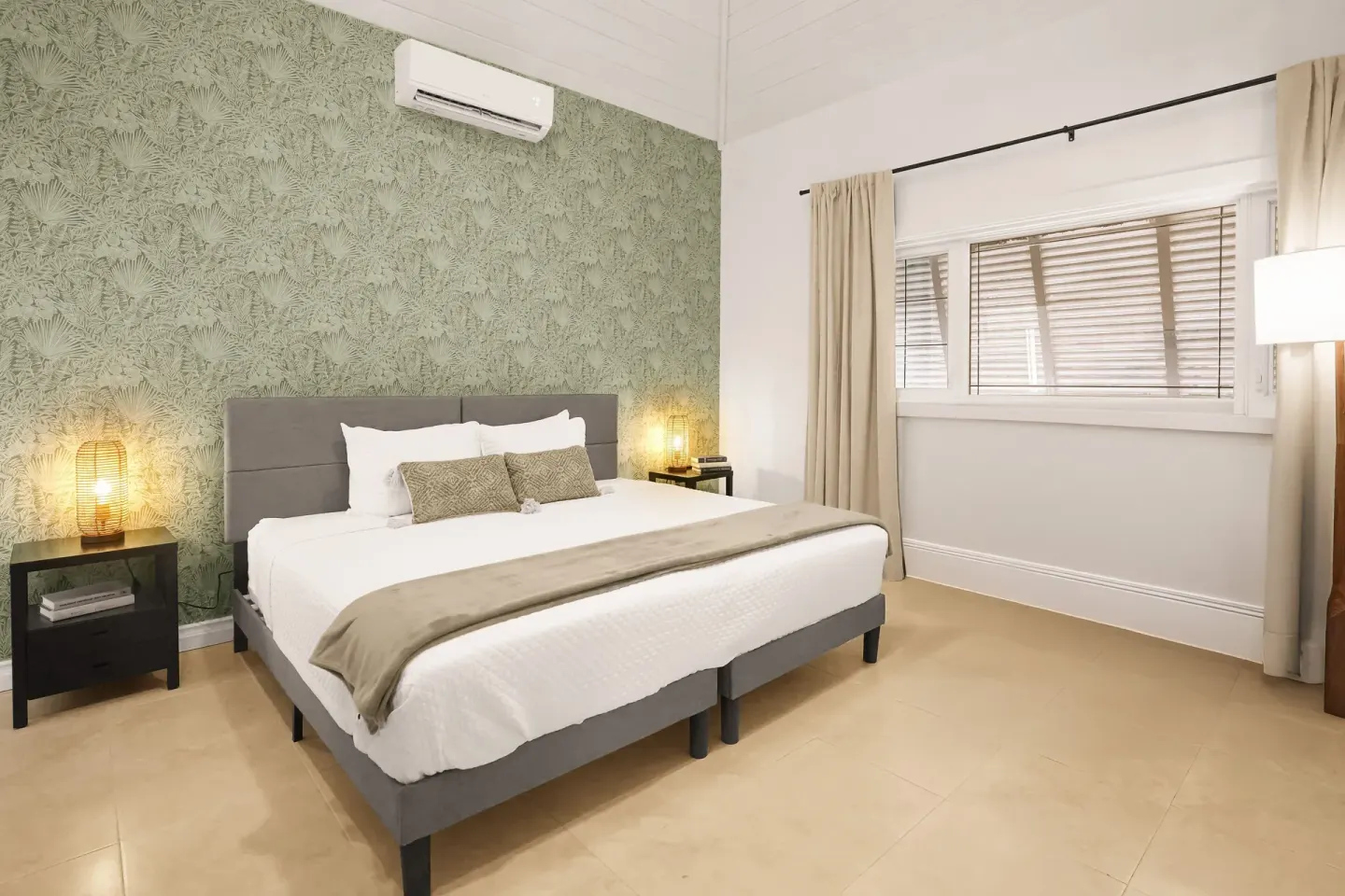 Standard Room king bed with lamps, window and patterned wall at Cobalt Coast Resort.