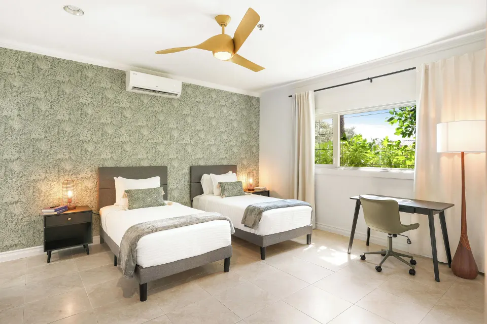 Standard Room with two twin beds, desk, and window greenery at Cobalt Coast Resort.