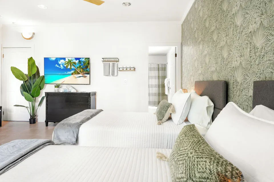 Standard Room twin beds with TV, dresser and open bathroom doorway at Cobalt Coast Resort.