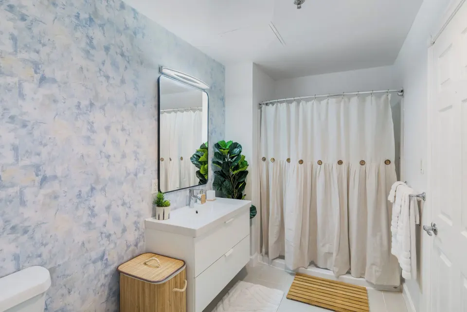 One Bedroom Suite bathroom with white vanity, mirror, shower curtain, and blue accent wall at Cobalt Coast Resort.
