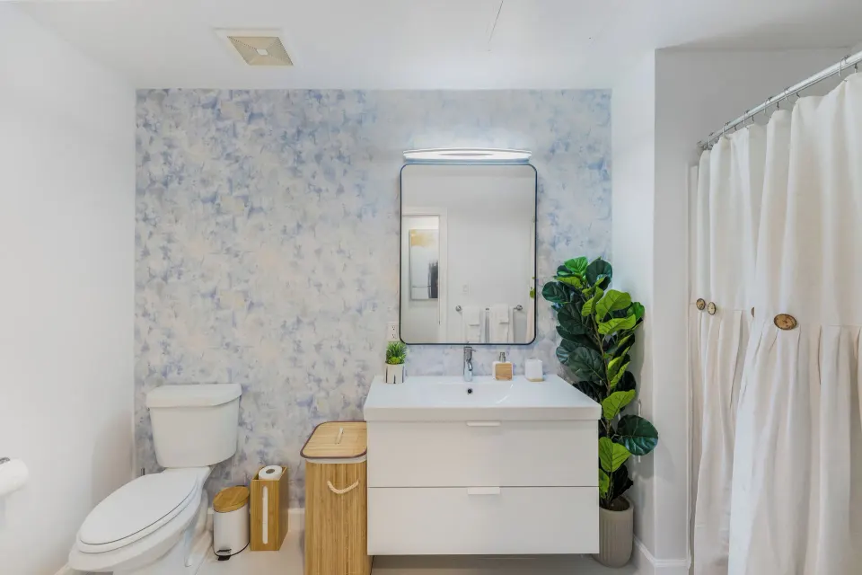 One Bedroom Suite bathroom with toilet, vanity, mirror, and shower curtain at Cobalt Coast Resort.