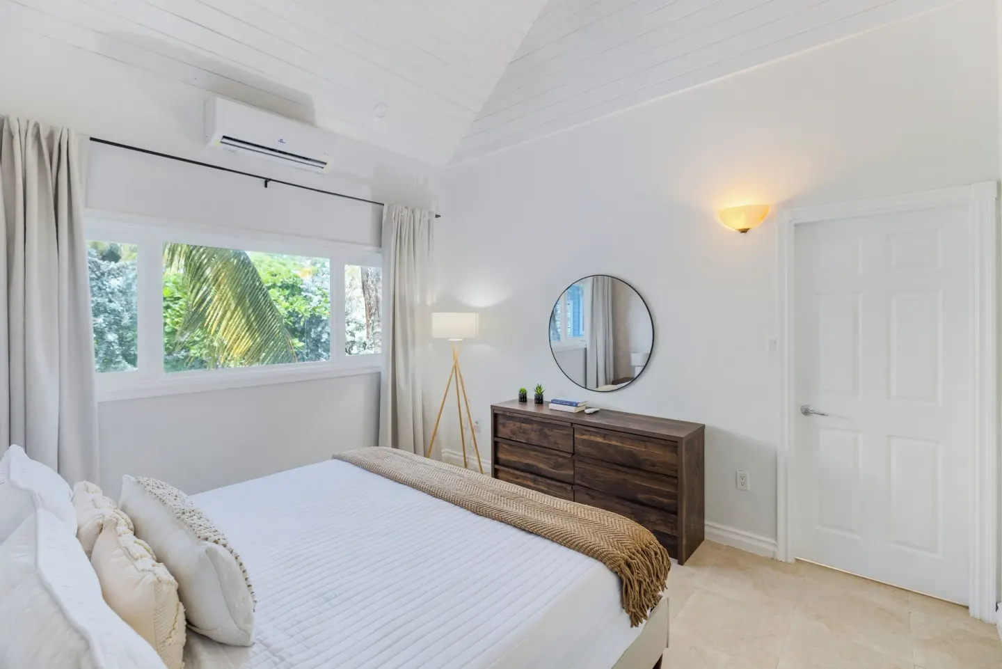 One Bedroom Suite king bed, dresser, round mirror, and wide window at Cobalt Coast Resort.