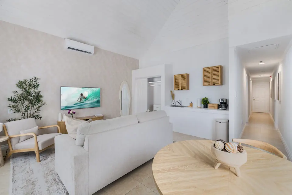 One Bedroom Suite living area with sofa, TV, dining table, and kitchenette at Cobalt Coast Resort.