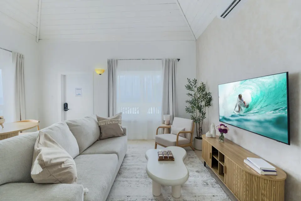 One Bedroom Suite lounge with sofa, coffee table, TV console, and accent chair at Cobalt Coast Resort.