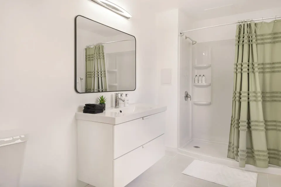 Two-bedroom suite bathroom with white vanity, mirror, and shower at Cobalt Coast Resort.