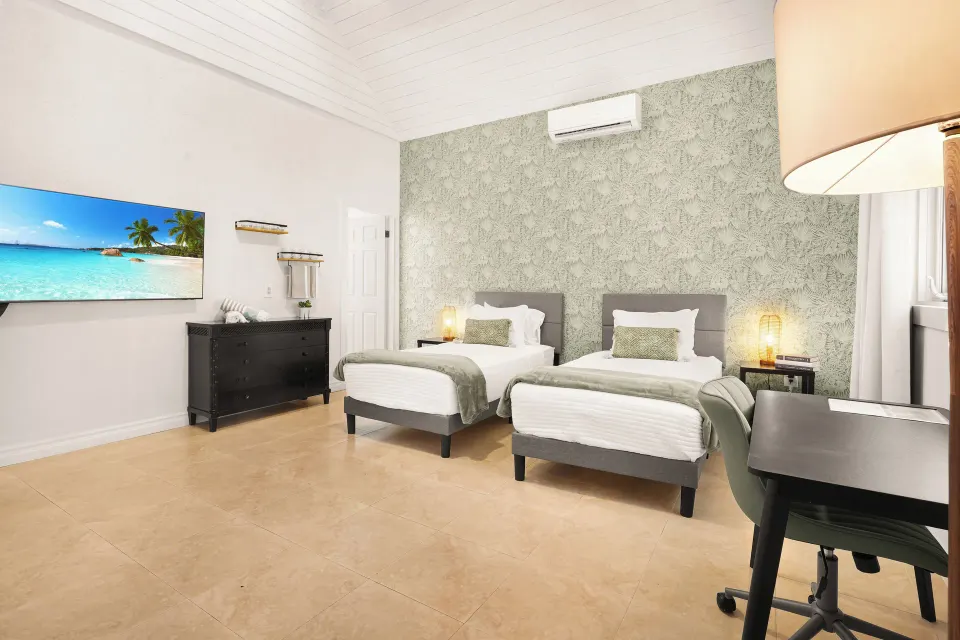 Two-bedroom suite room with twin beds, desk, TV, and patterned wall at Cobalt Coast Resort.
