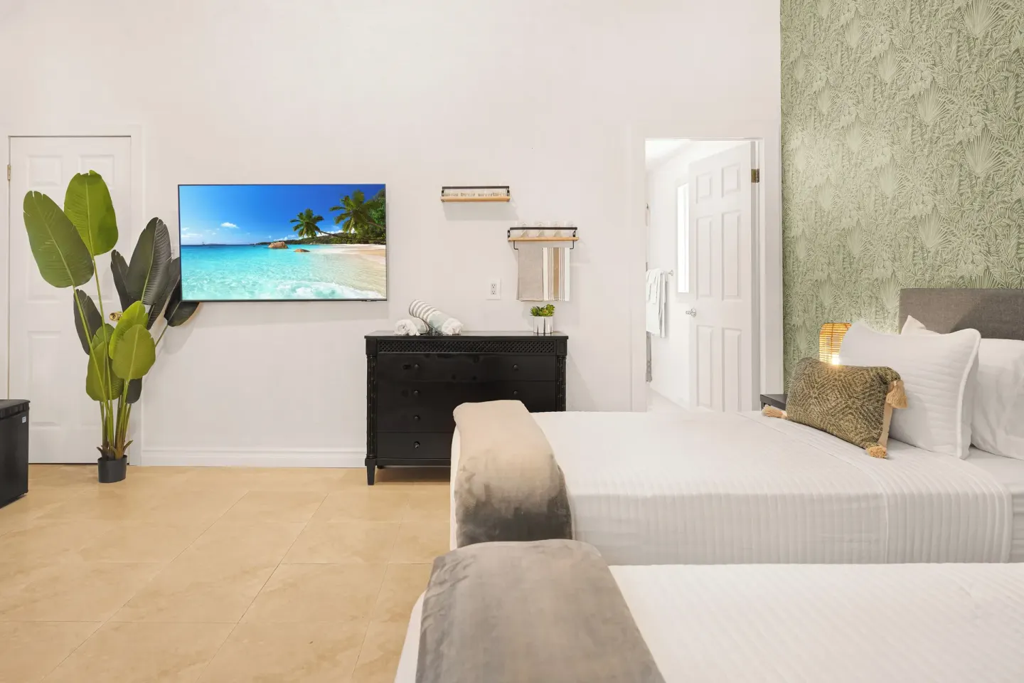 Two-bedroom suite bedroom with two beds, TV, dresser, and plant at Cobalt Coast Resort.