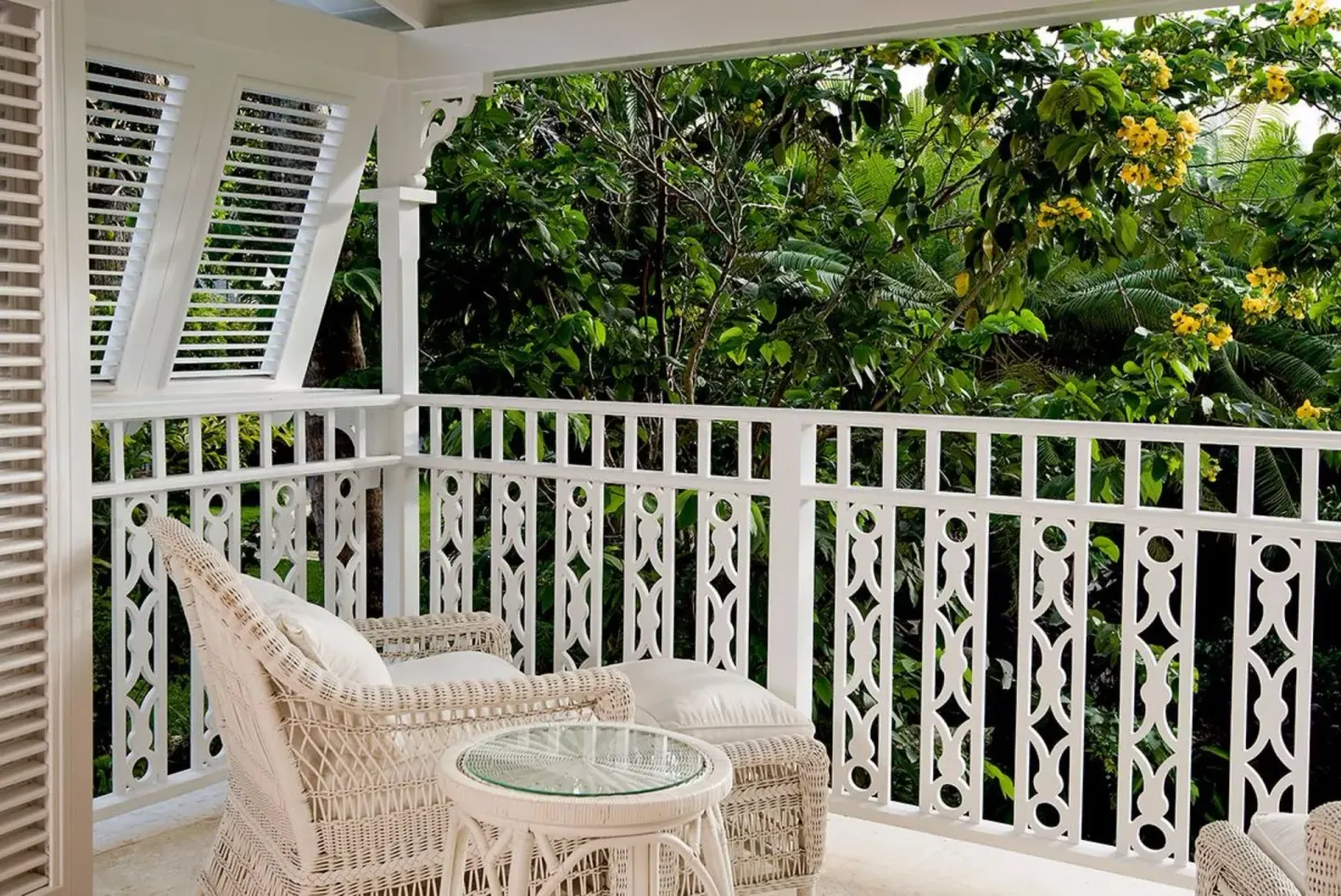 Garden-facing balcony with wicker chair and white railing at Cobblers Cove.