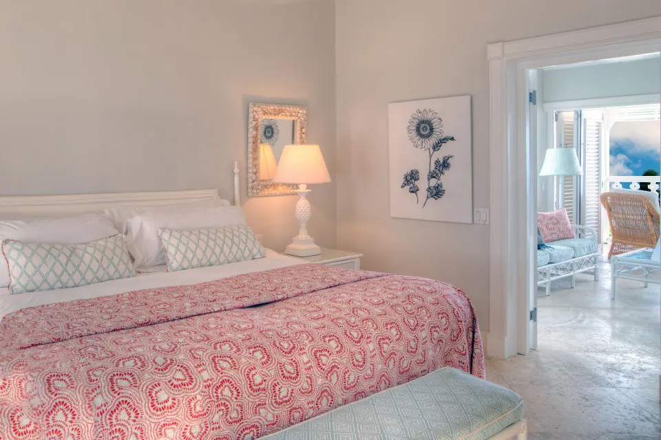 Guest room with a white bed and adjoining sitting area at Cobblers Cove.