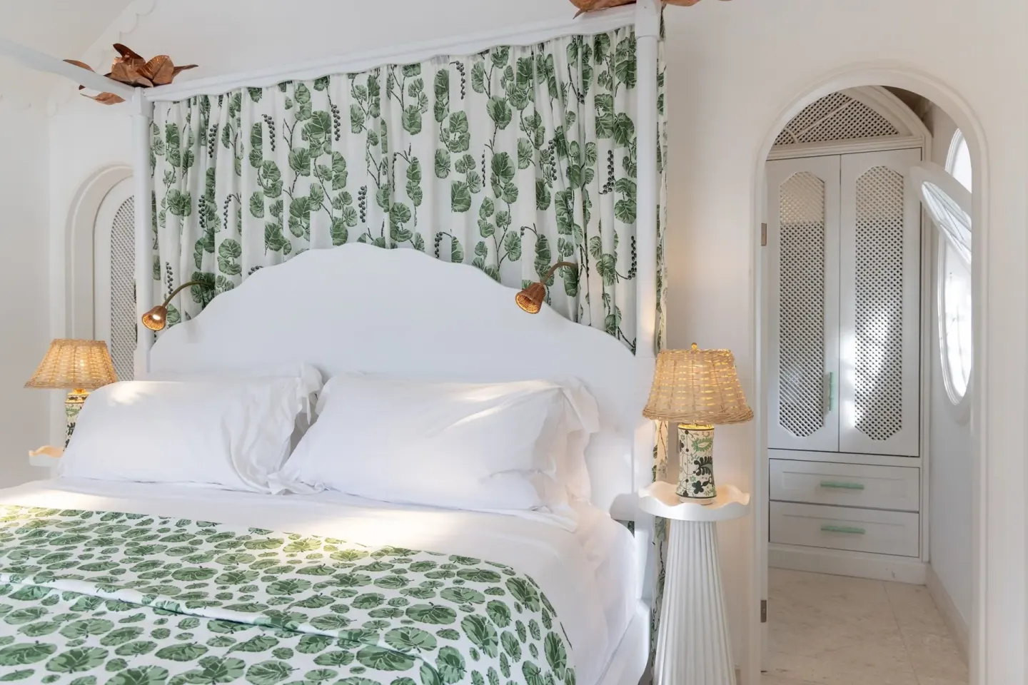 Guest room bed with green botanical fabrics and arched wardrobe at Cobblers Cove.
