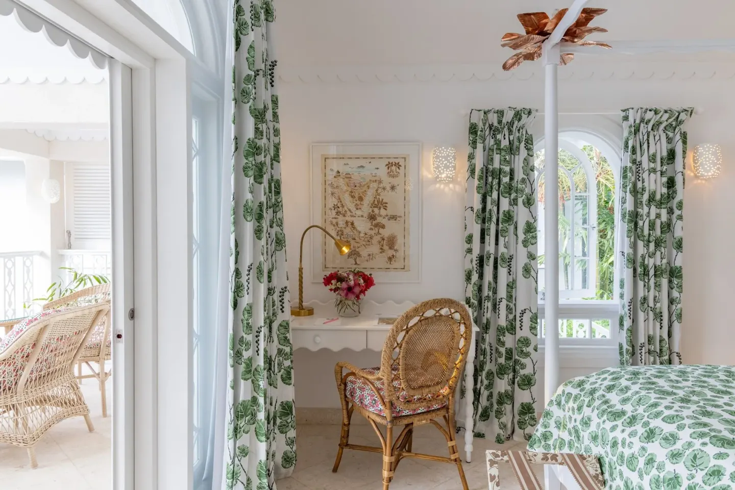 Guest room writing desk, balcony door, and green botanical bed linens at Cobblers Cove.