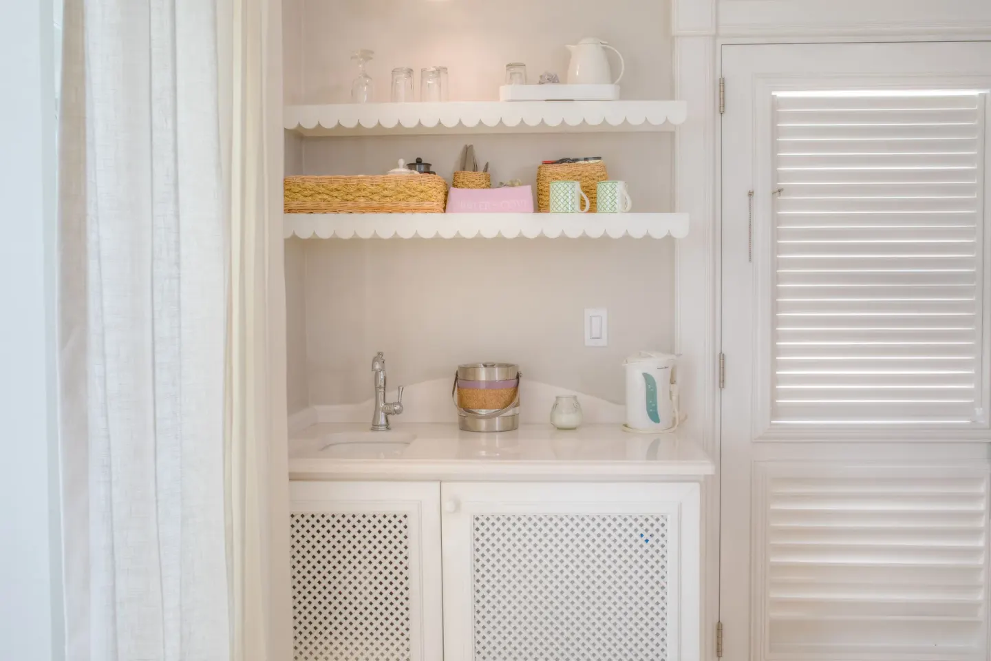 Guest room refreshment station with sink, shelves, kettle and shuttered door at Cobblers Cove.